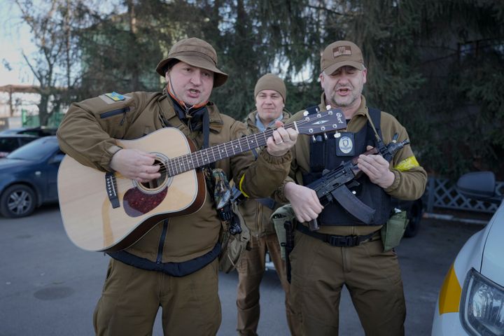Members of the Ukrainian civil defense, one mimicking a guitar with his assault rifle, play a song while waiting to escort a fuel transport in Kyiv, Ukraine, Monday, Feb. 28, 2022. (AP Photo/Vadim Ghirda)