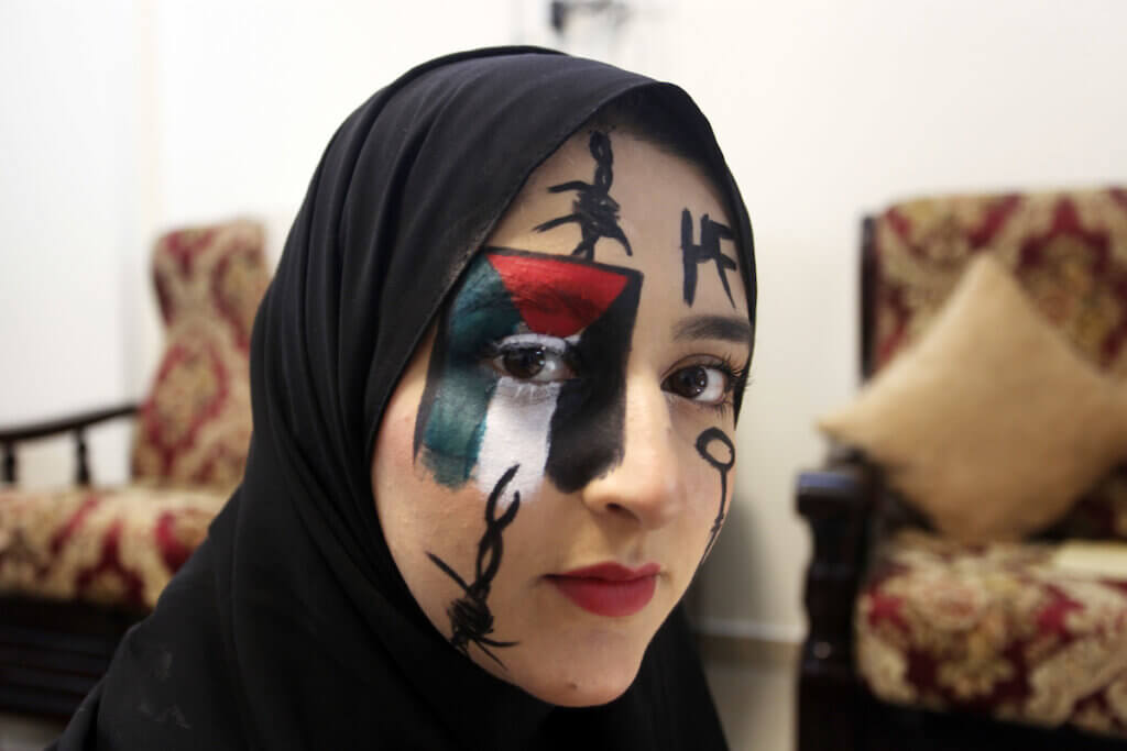 Palestinian artist and refugee Lana Awad, 24, paints her face to mark World Refugee Day, at her home in Gaza City on June 20, 2022. (Photo: Omar Ashtawy/APA Images)