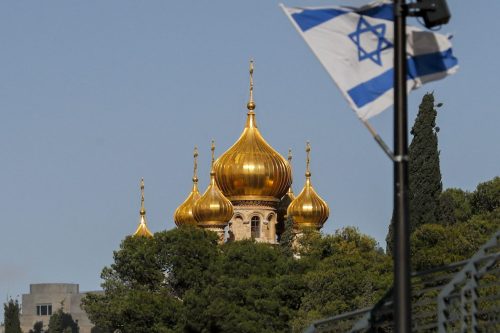 This picture taken on December 20, 2021 shows a view of an Israeli flag flying near the Russian Orthodox Church of Mary Magdalene atop the Mount of Olives in Jerusalem. [AHMAD GHARABLI/AFP via Getty Images]
