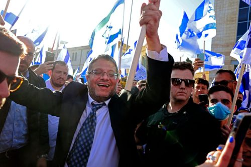 Israeli far-right lawmaker and leader of the Otzma Yehudit party Itamar Ben-Gvir, raises an Israeli flag oin Safra square in Jerusalem on April 20, 2022 [MENAHEM KAHANA/AFP via Getty Images]