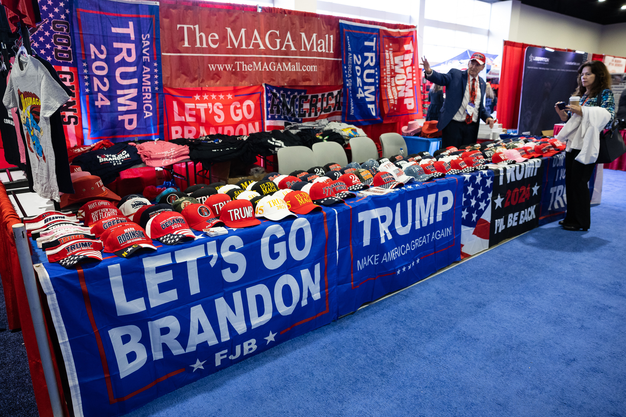 Ronald Solomon speaks with Lisa Giulianelli at his merchandise stand at the Conservative Political Action Conference (CPAC) at the Gaylord National Resort and Convention Center in National Harbor, Md. on March 2, 2023.