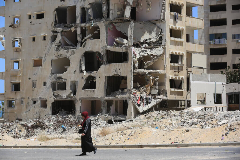 A woman walks across a street in Gaza City with Hanadi Tower in the background, a residential tower that was hit by Israeli strikes during the 11-day Israeli war on Gaza in May 2021. Photo taken on May 10, 2022.