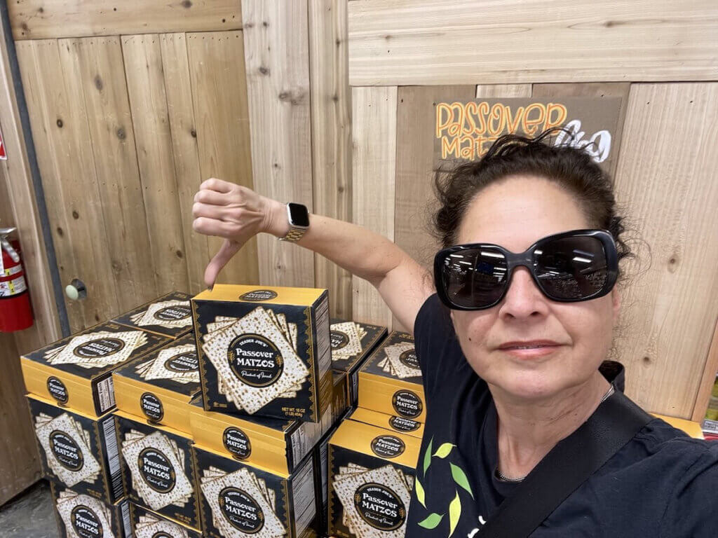 Activist Estee Chandler flashes the thumbs down gesture in a selfie photo in front of a display of Israeli motzo at Trader Joe's.