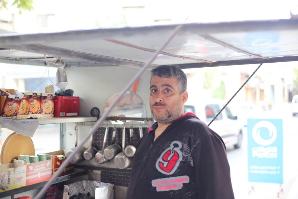 Ameen Qaddoum, 50, leans over his stall and makes tea and coffee on the street in a residential neighborhood in al-Shuja;iyya.