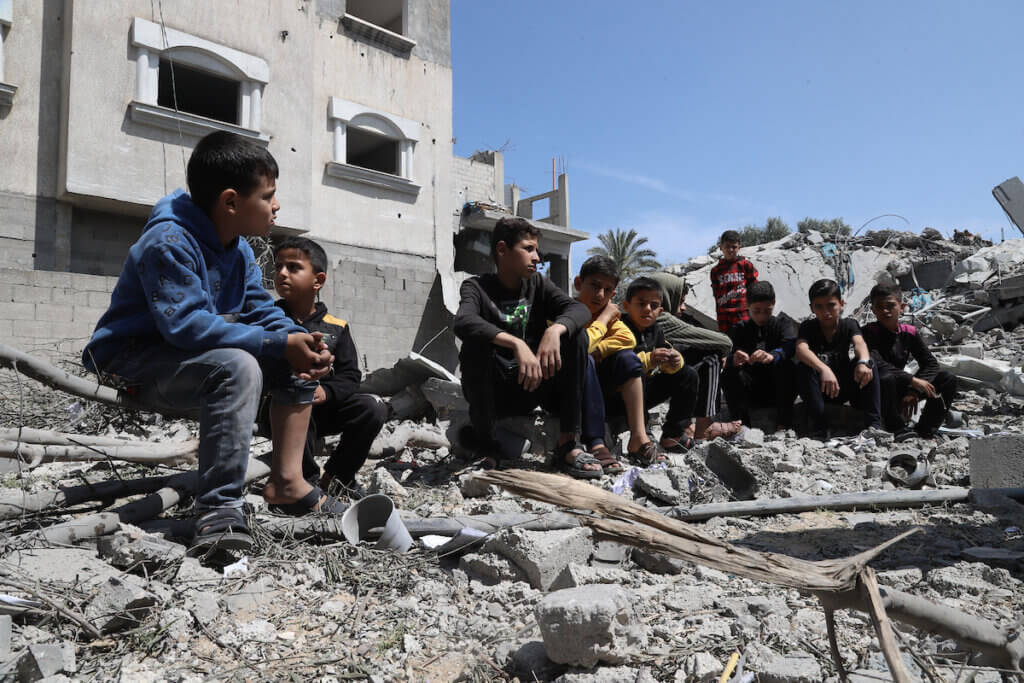 Children sit amidst the rubble of their home, which was destroyed in an Israeli airstrike in Deir al-Balah in May 2023.